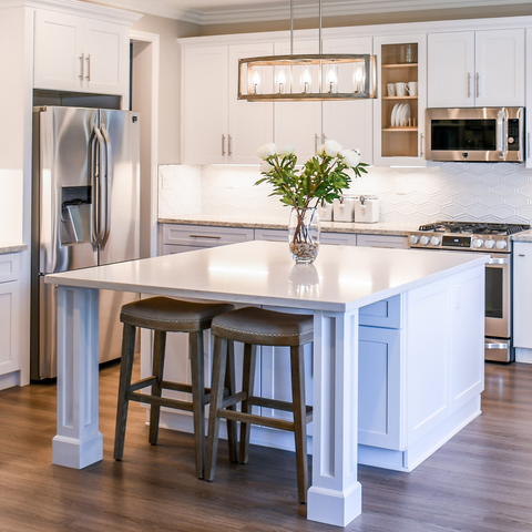 Kitchen island with white countertop decorated with flowers, also featuring hardwood floor and stainless steel appliances, along with warm lighting.