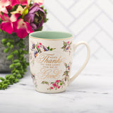 Floral Pastel Scripture Inscribed Ceramic Coffee Mug with Bible verse Psalm 107:1  with Flowers and Planter in background. ral PBa